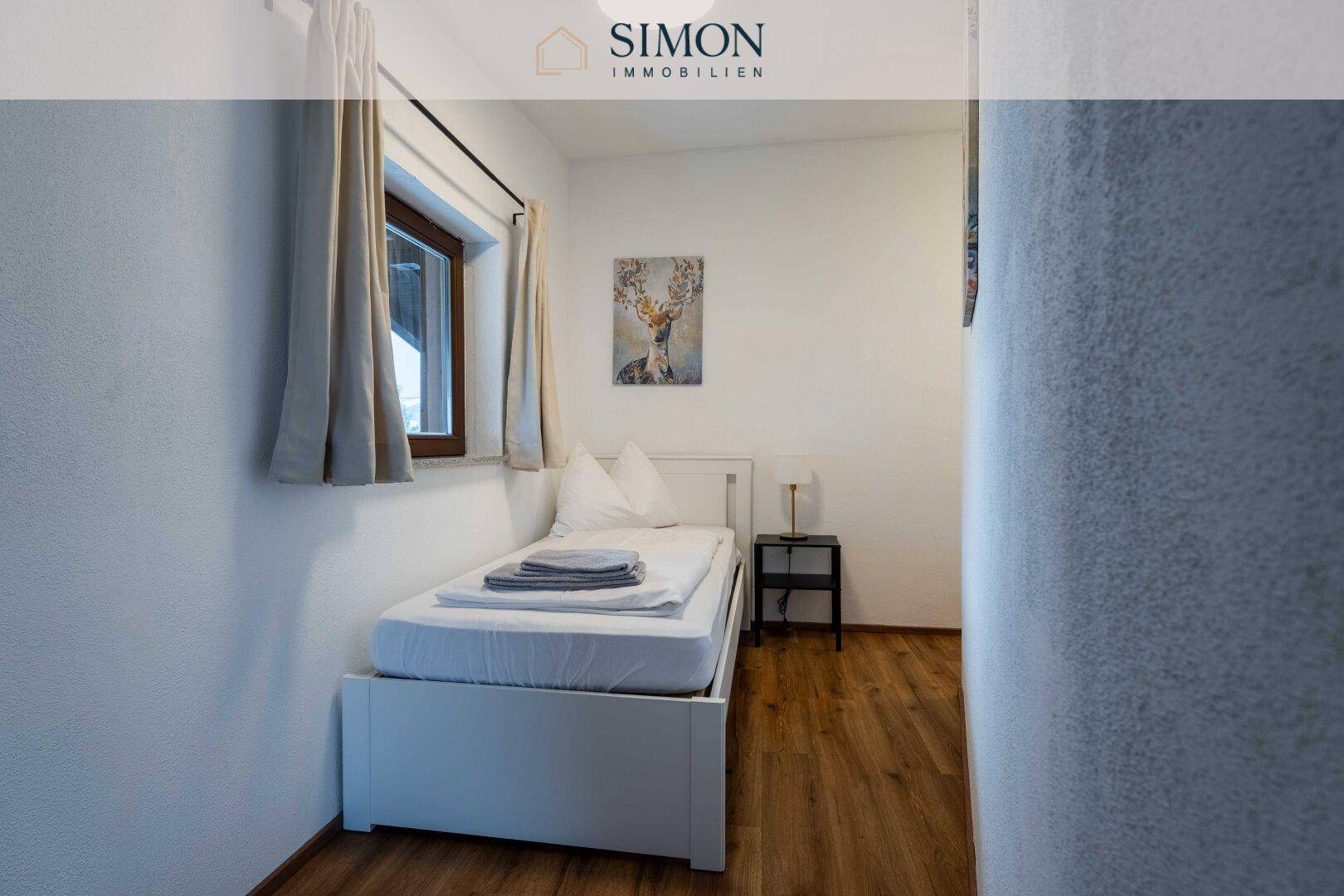 Einzelzimmer mit Bett, Nachttisch und Fenster, ideal als Kinder- oder Gästezimmer.