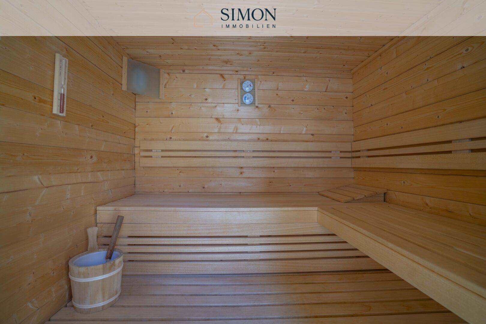 Innenansicht der Holzsauna mit Bänken und traditionellem Saunaeimer.