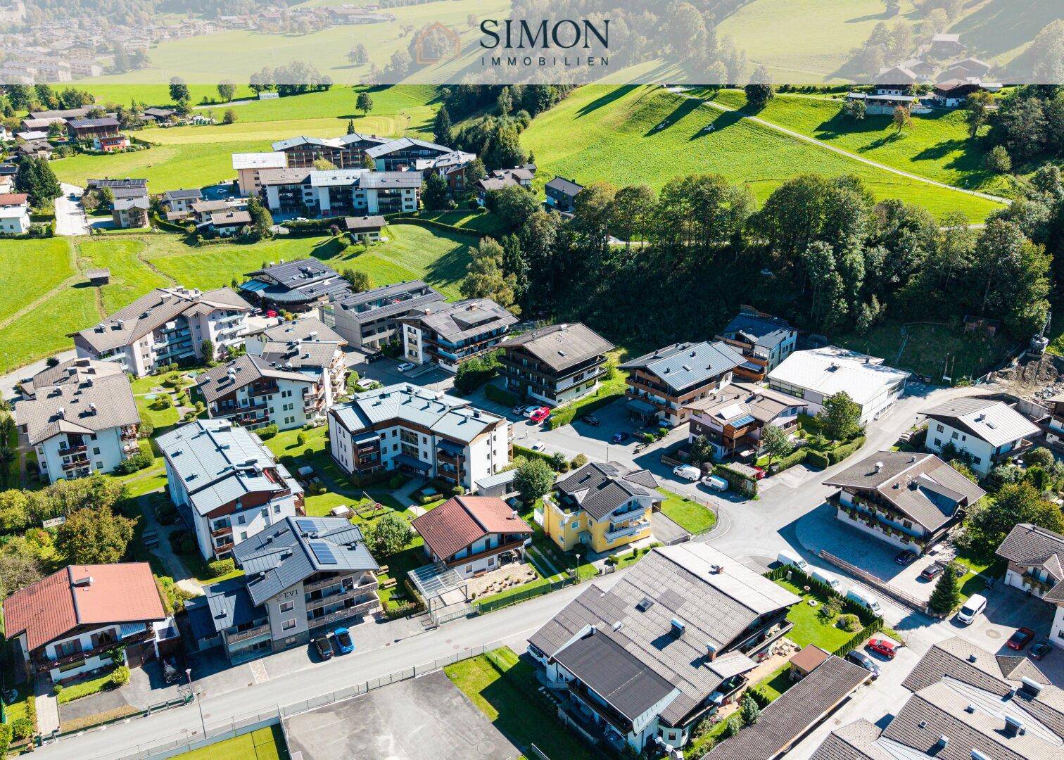 Panoramablick aus der Luft auf eine ländliche Siedlung mit vielen Häusern und weitläufigen grünen Feldern.