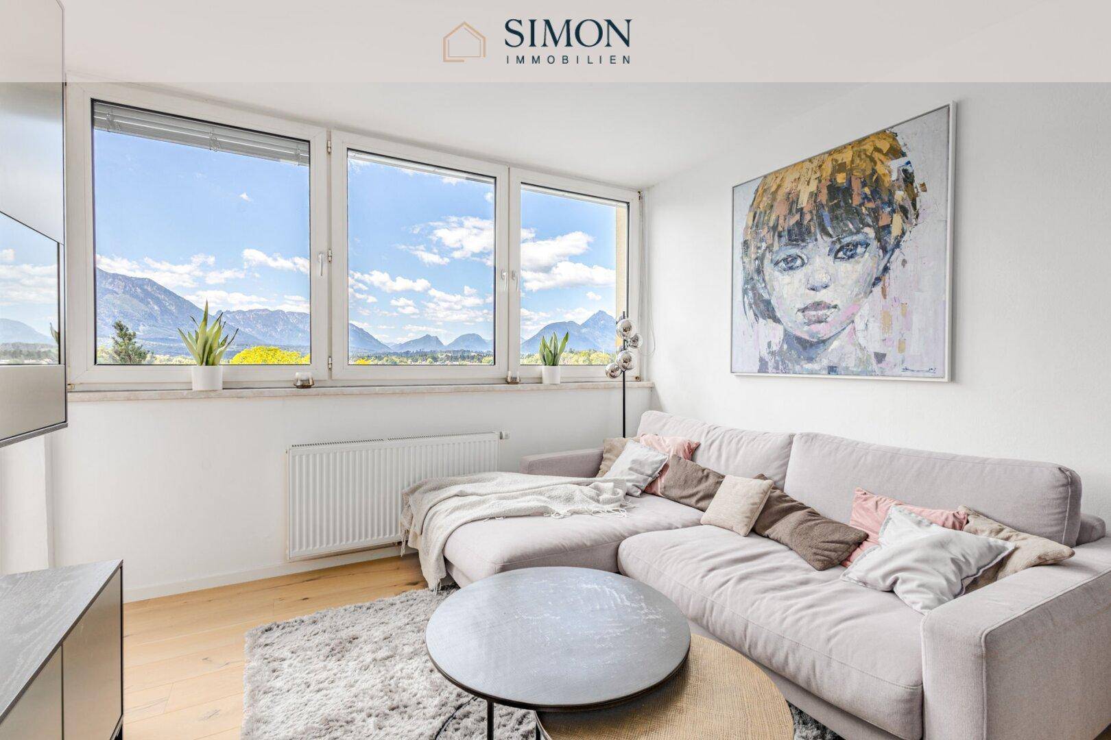 Gemütliches Wohnzimmer mit großem Sofa, Holzboden und weitem Bergblick durch die Fenster.