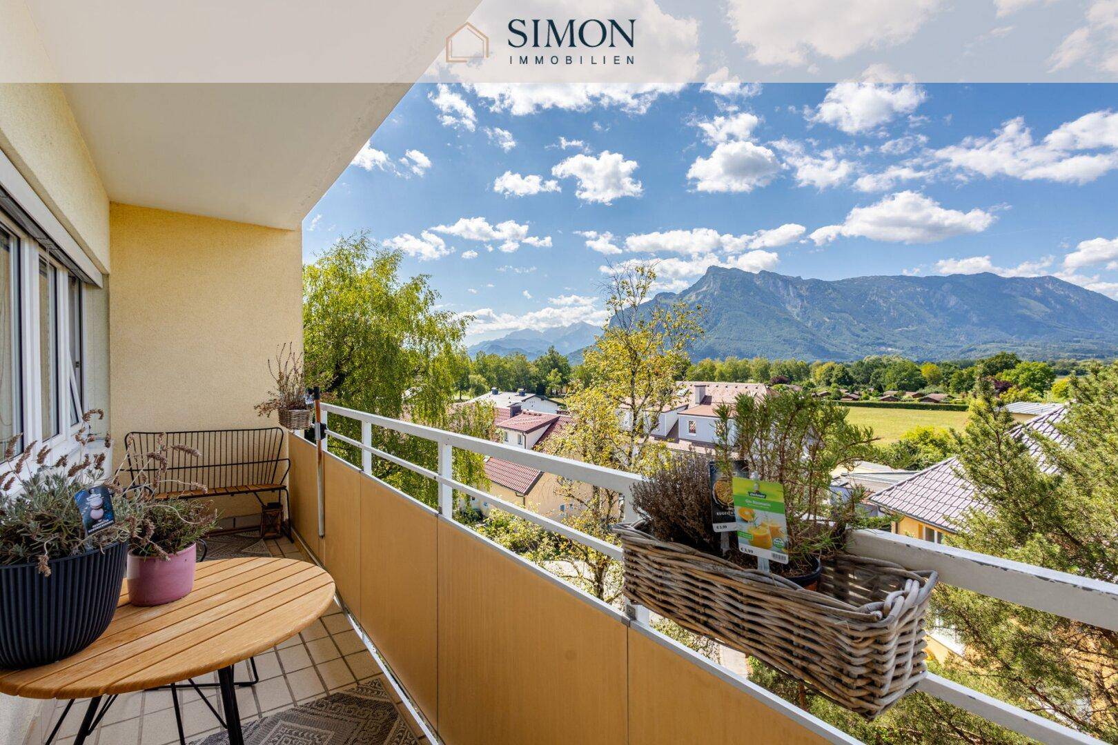 Möblierter Balkon mit Tisch und Stühlen, bietet einen weiten Bergblick und viel Grün.