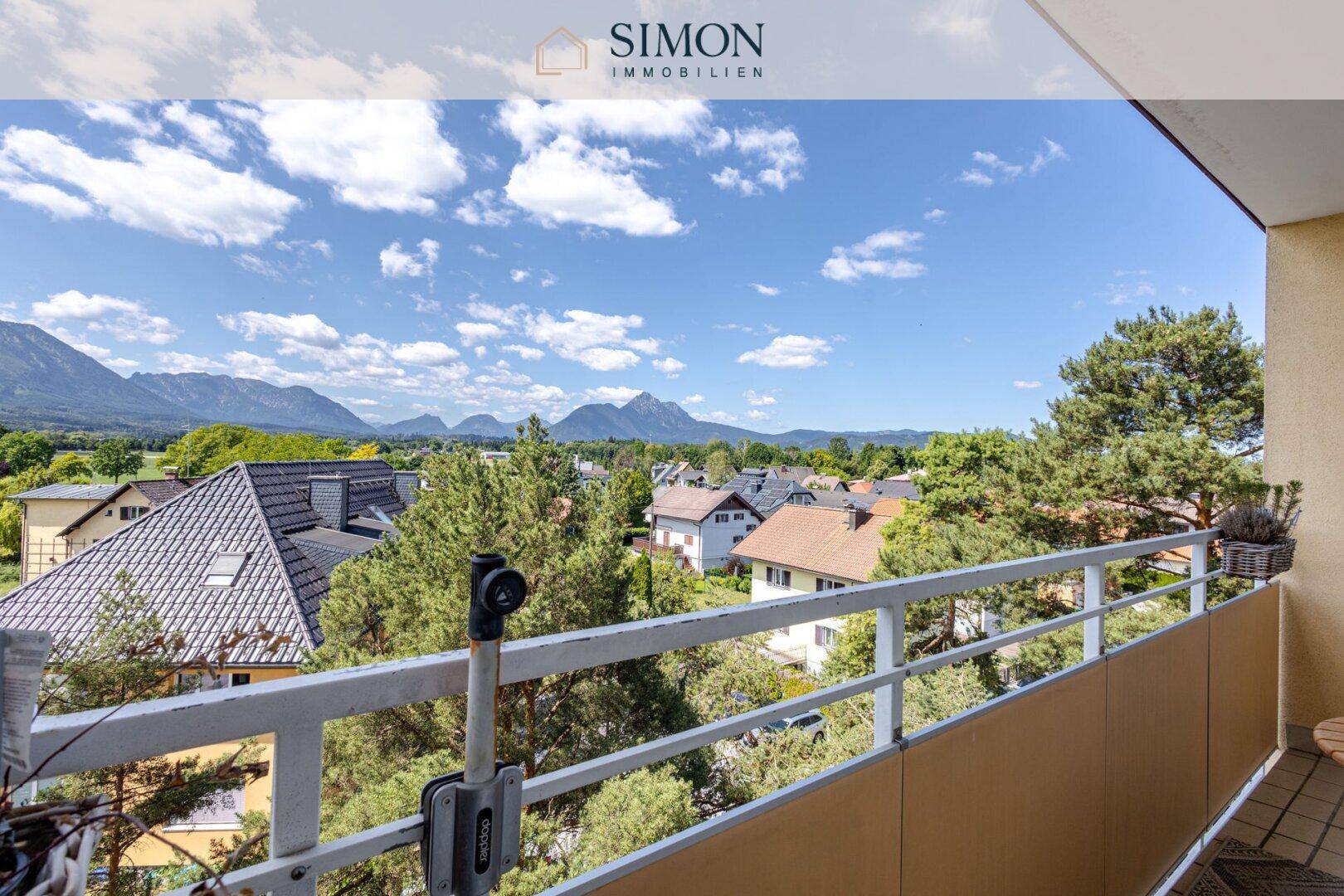 Geräumiger Balkon mit Panoramablick auf die umliegende Berglandschaft und die Dächer der Häuser.