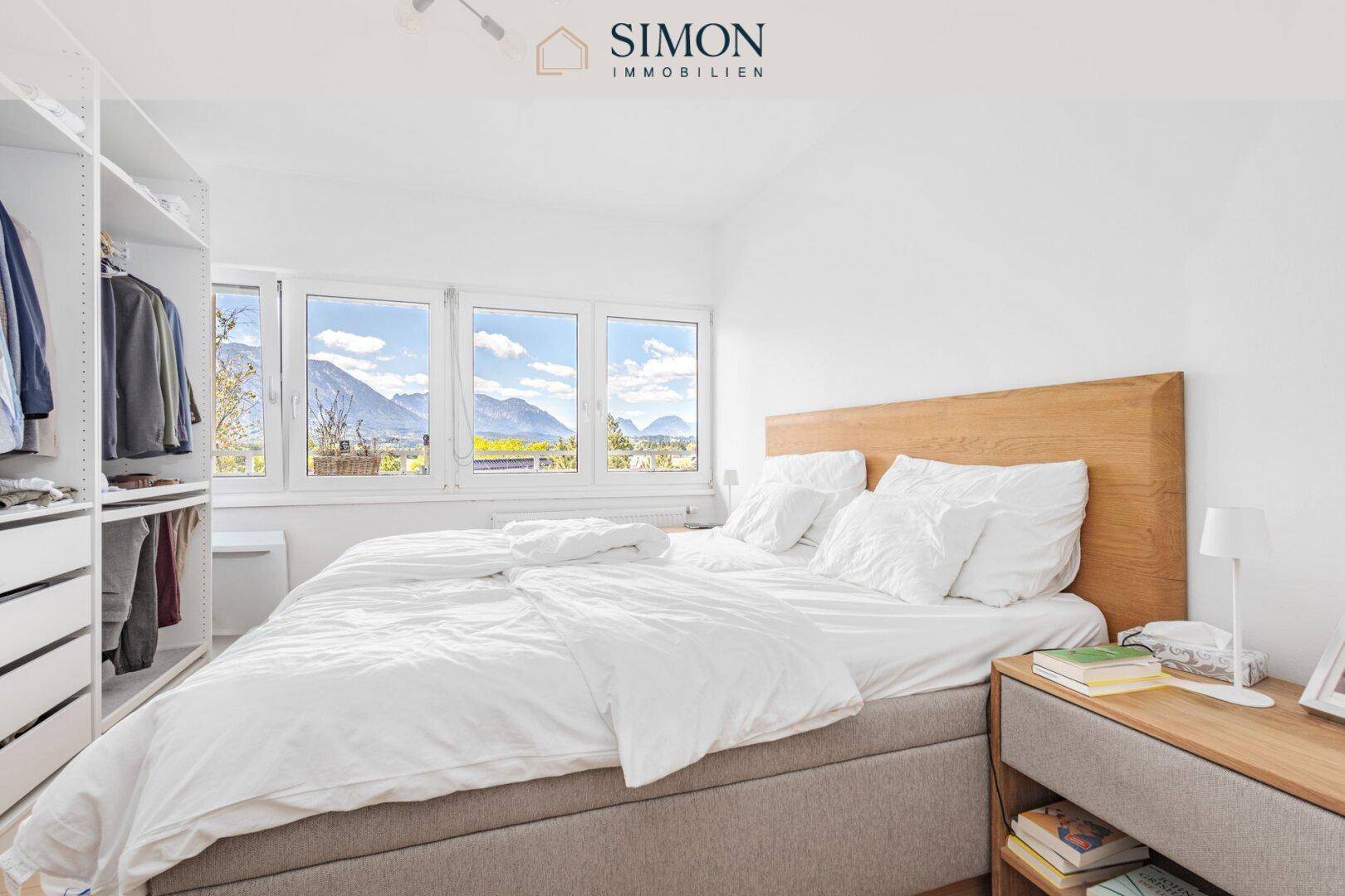 Helles Schlafzimmer mit Doppelbett, Einbauschrank und Bergblick durch große Fenster.