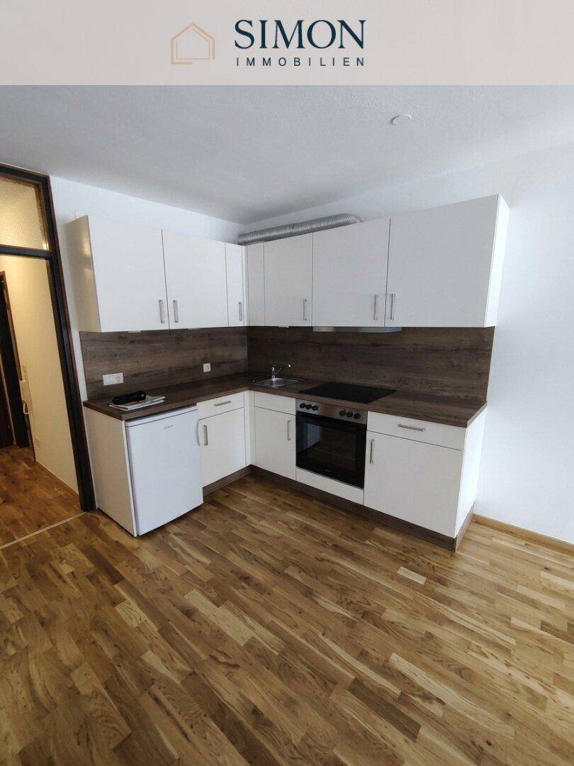 Funktionale Küche mit weißen Schränken, Holzoptik-Arbeitsplatte und integrierten Geräten.