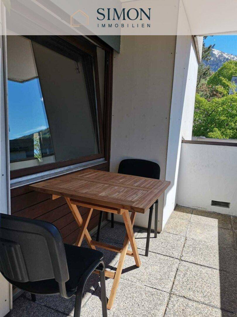 Gemütlicher Balkon mit kleinem Holztisch, Stühlen und einem schönen Bergblick.
