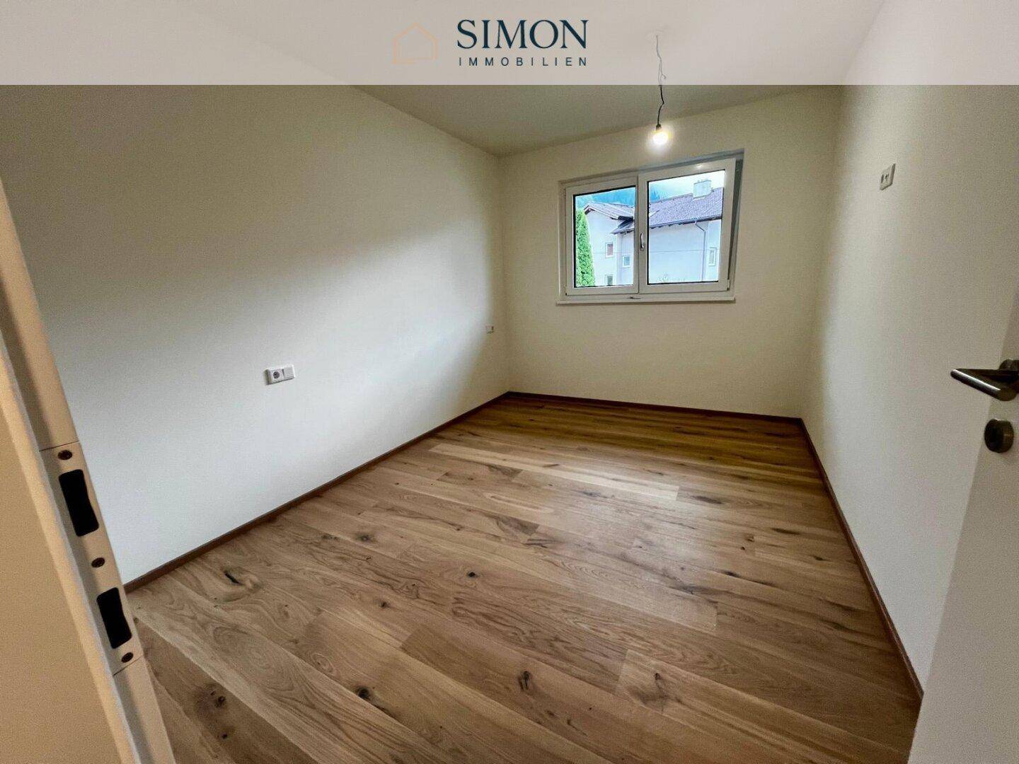 Geräumiges Zimmer mit neuem Holzfußboden und Fenster, bereit zur individuellen Gestaltung.
