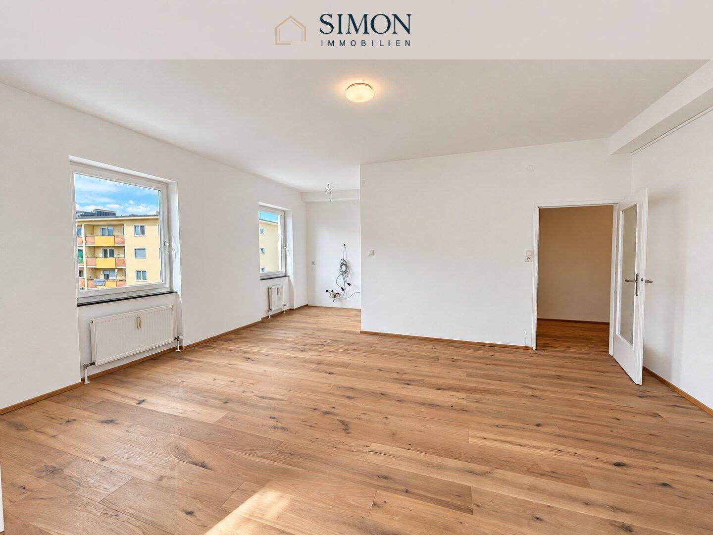 Geräumiges Wohnzimmer mit Holzboden und mehreren Fenstern, bereit für die Gestaltung.