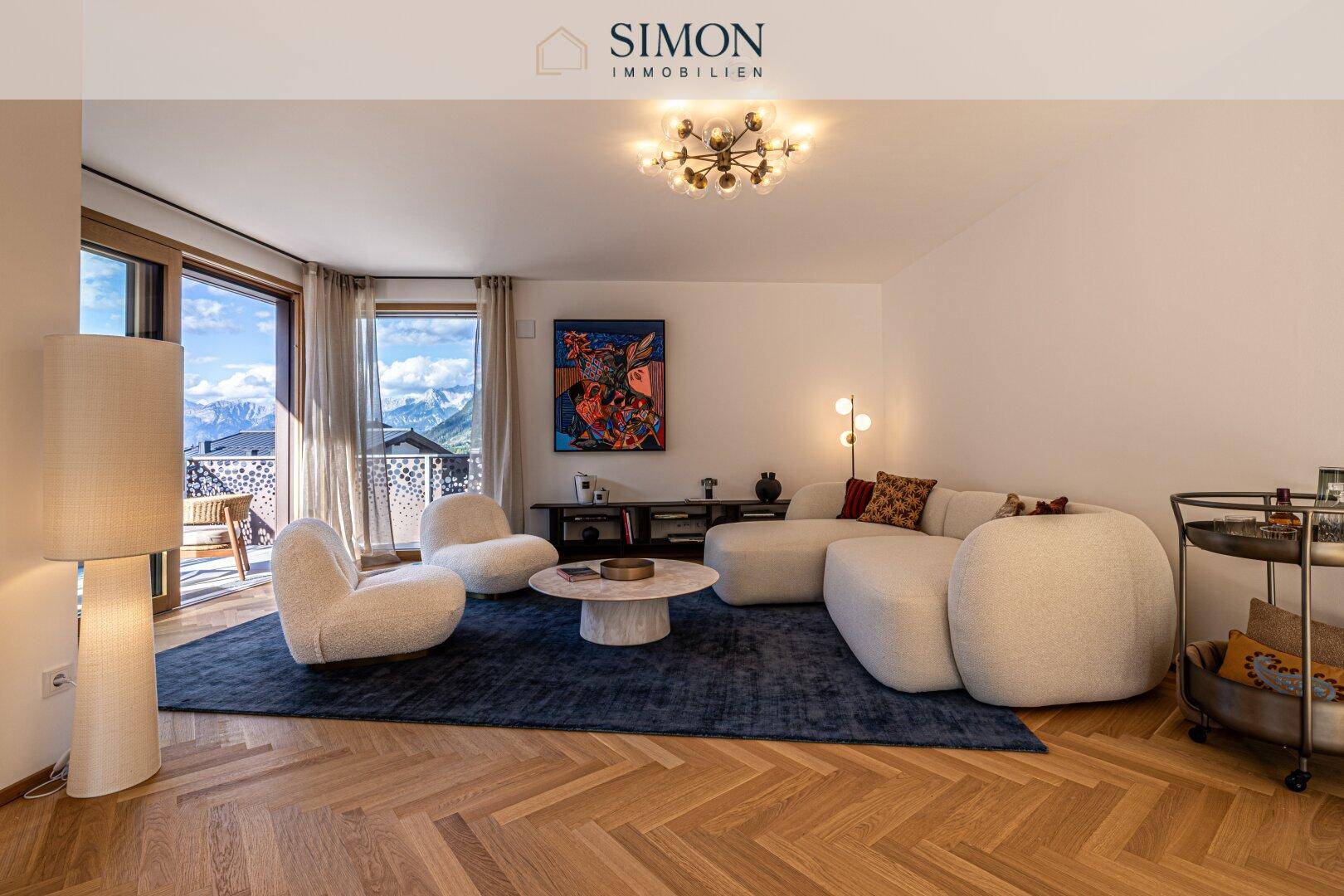 Gemütliches Wohnzimmer mit modernem Sofa, Teppich und großzügigen Fenstern mit Bergblick.