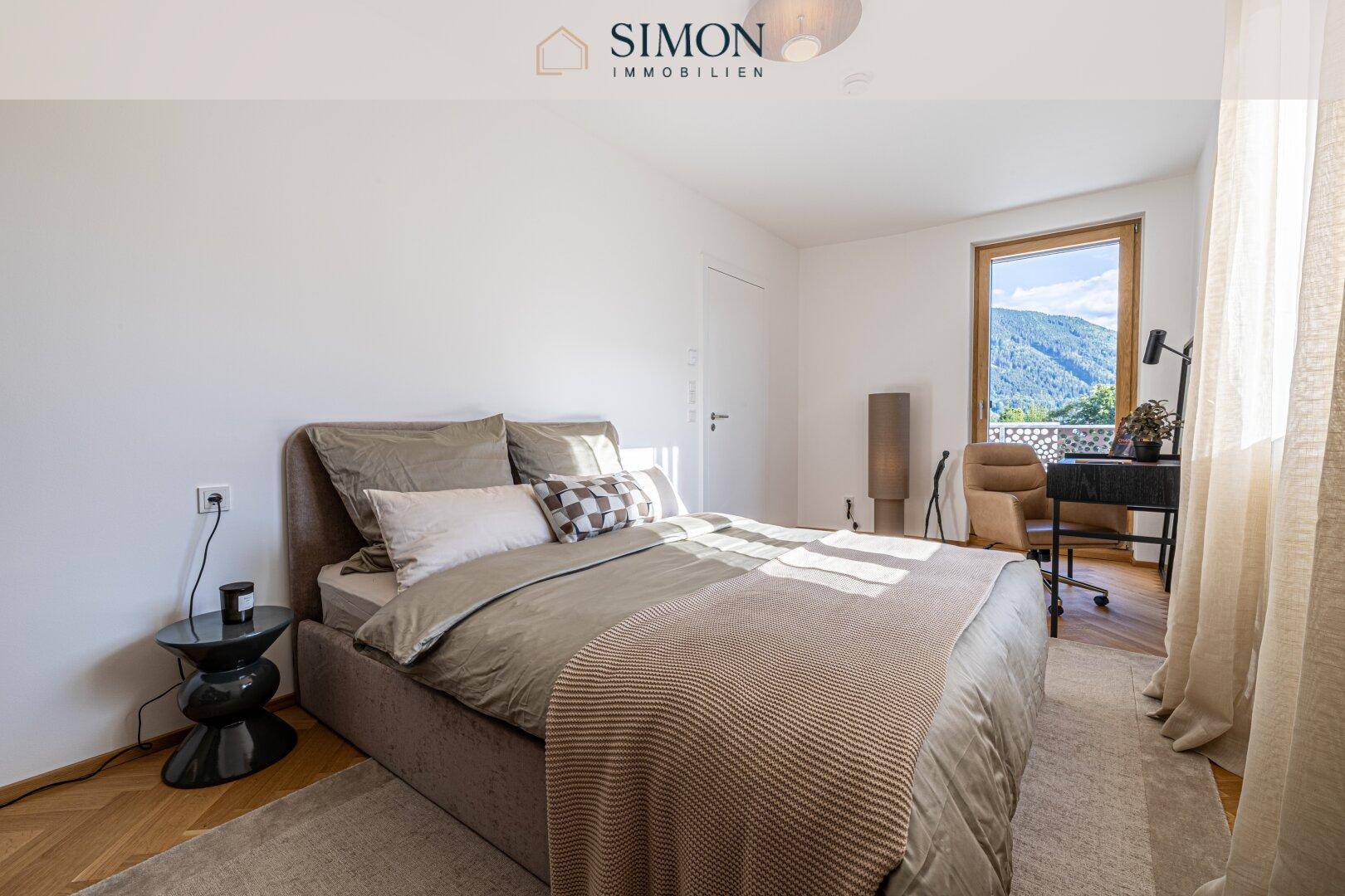 Helles Schlafzimmer mit Doppelbett, Schreibtisch und Fenster mit Blick auf die Berge.