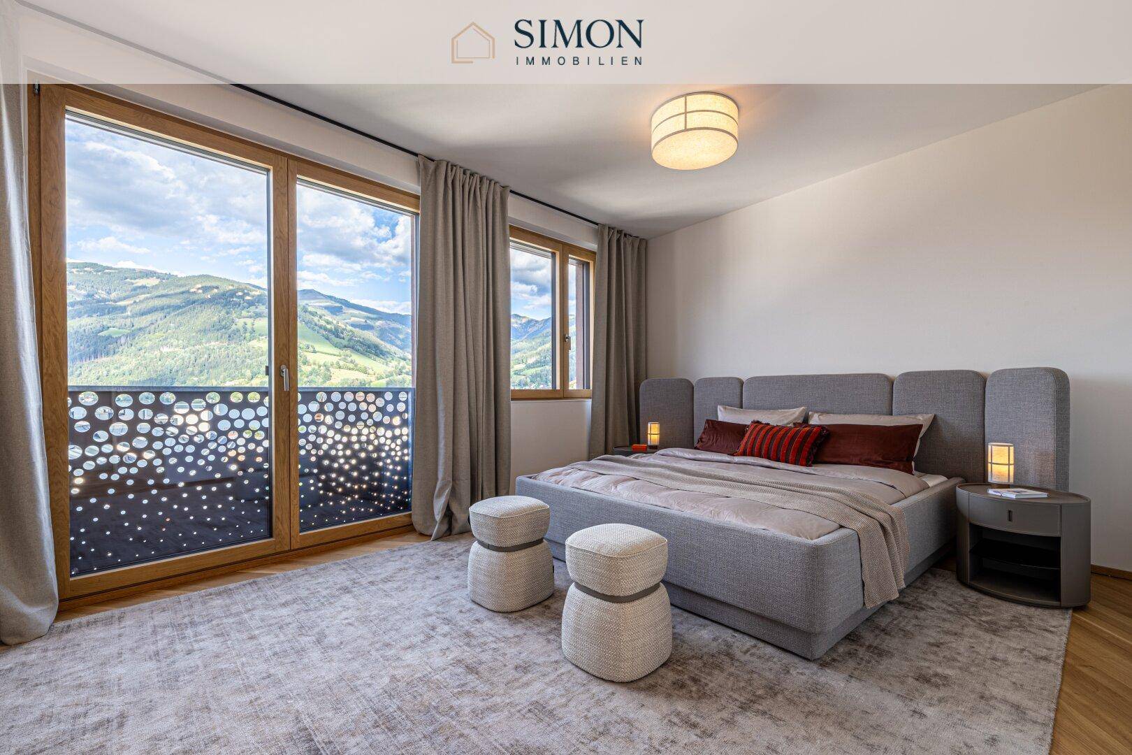 Modernes Schlafzimmer mit großem Bett, Teppich und Balkonzugang mit Bergblick.