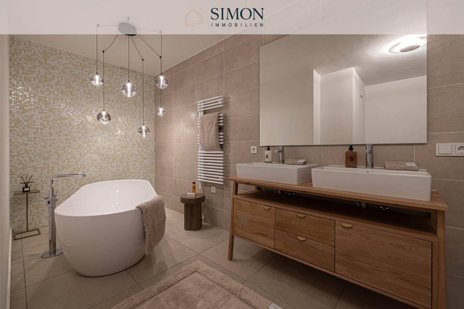 Modernes Badezimmer mit freistehender Badewanne, Doppelwaschbecken und Mosaikfliesen an der Wand.