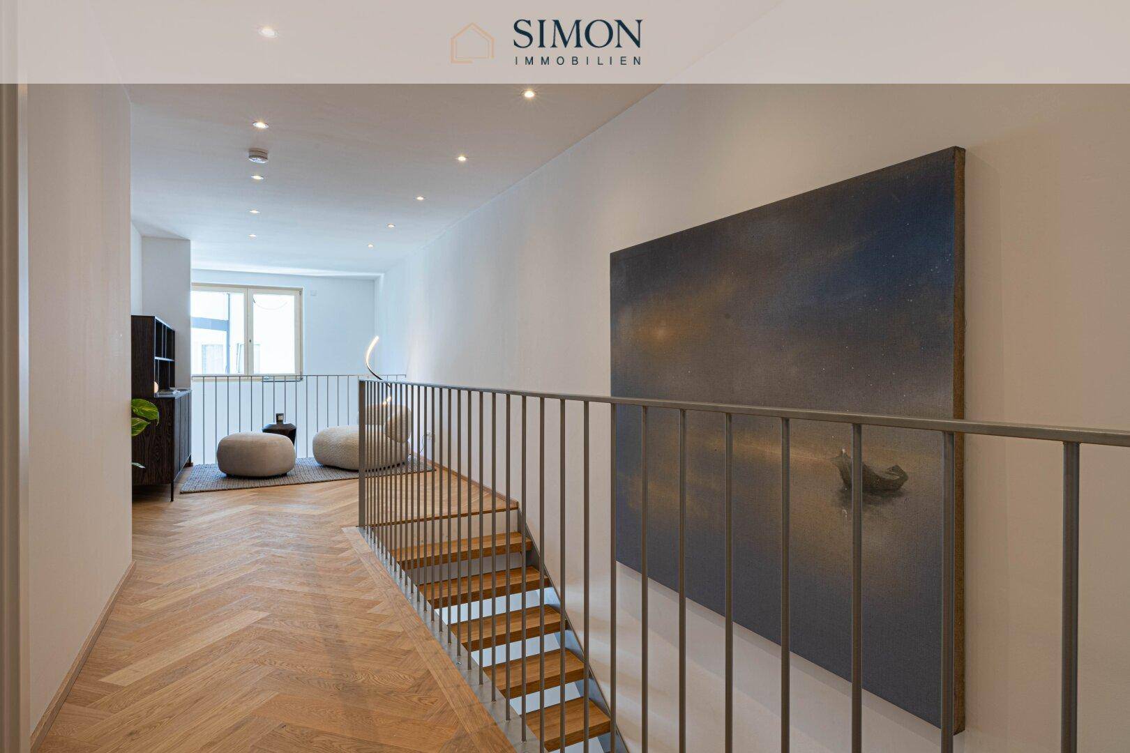 Heller Flur mit Holztreppe, modernem Geländer und Kunstwerk an der Wand.