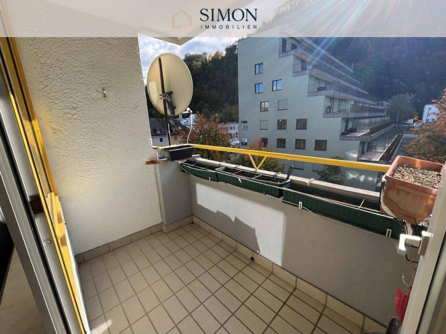 Balkon mit Fliesenboden, Satellitenschüssel und Blick auf die umliegenden Gebäude.