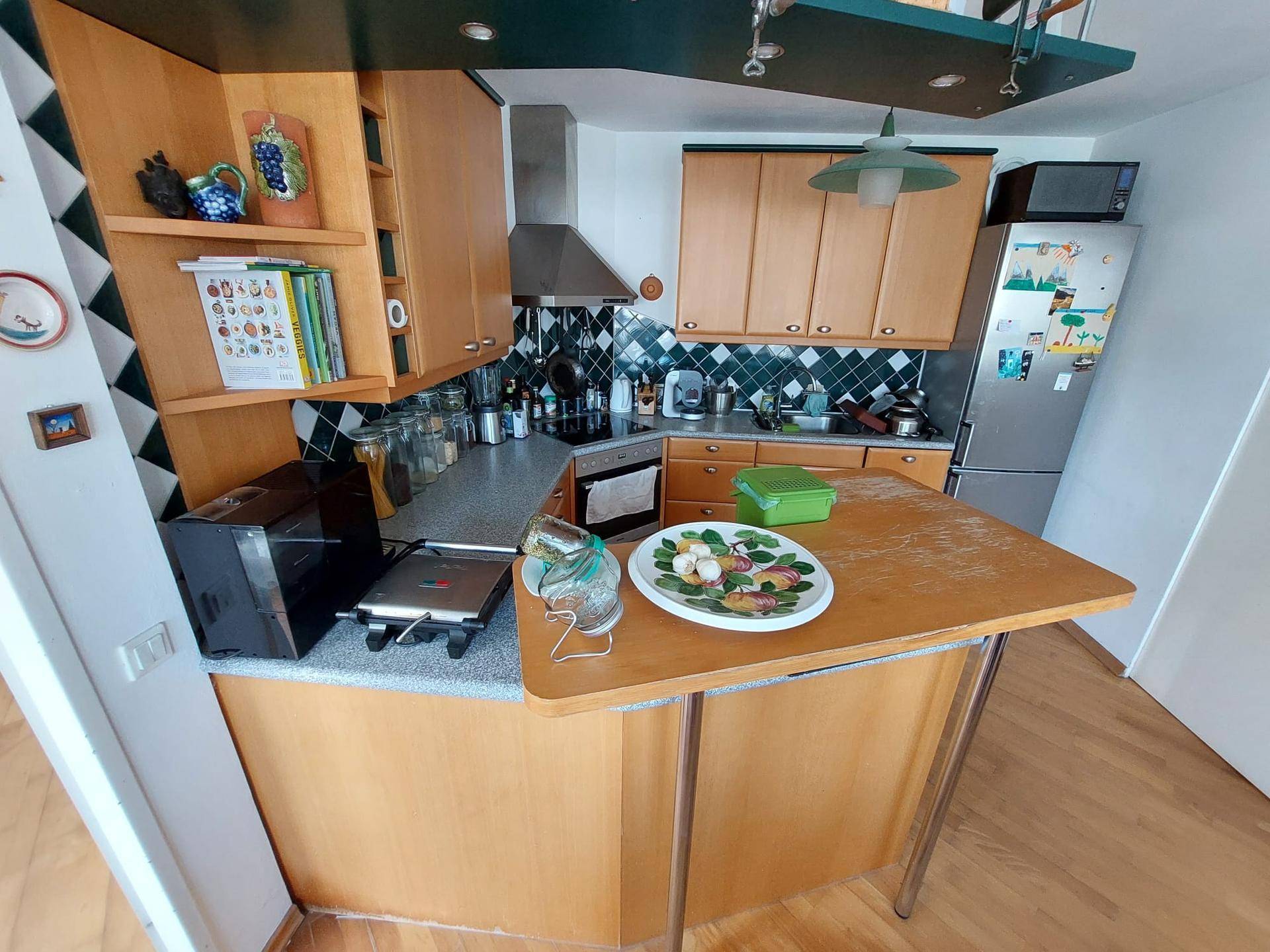 Funktionale Küche mit Holzschränken, dunklem Fliesenspiegel und einer kleinen Frühstückstheke.