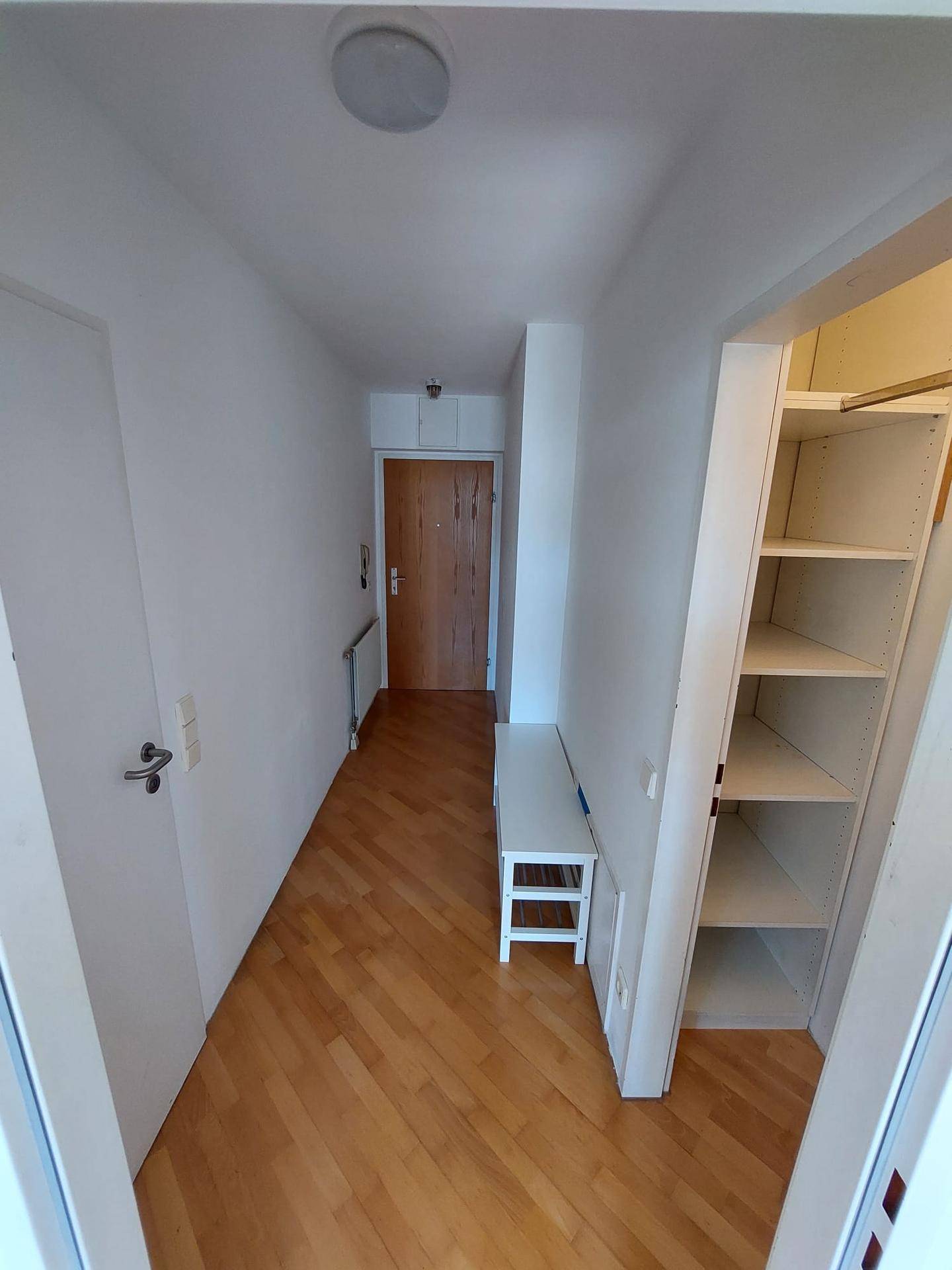 Heller Flur mit Parkettboden, weißen Wänden und praktischen Einbauregalen für zusätzlichen Stauraum.