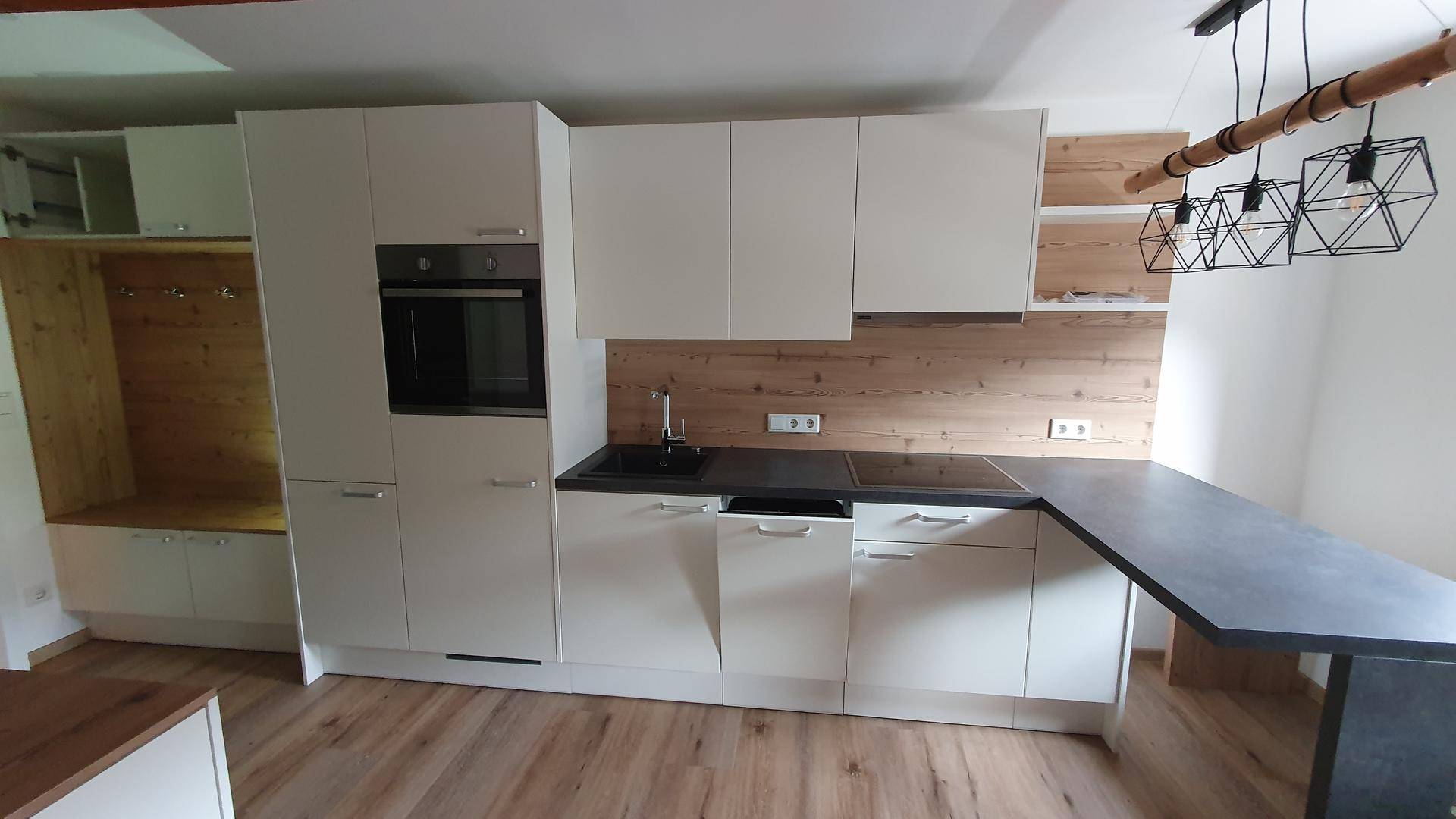 Detailansicht der modernen Einbauküche mit Spüle, Kochfeld und Backofen in weißer Ausführung.