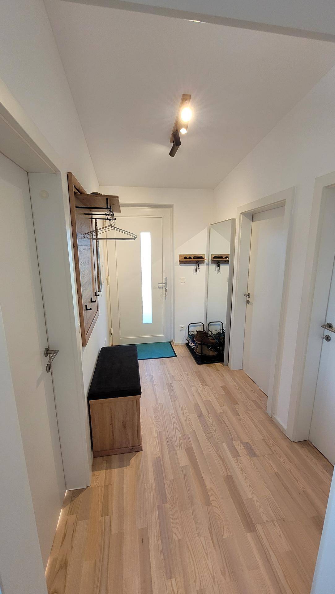 Heller Eingangsbereich mit hellem Holzboden, Garderobe und viel natürlichem Licht.