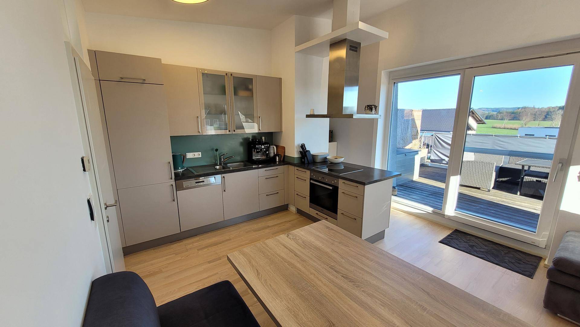 Funktionale Einbauküche mit modernen Geräten und direktem Zugang zur Außenterrasse.