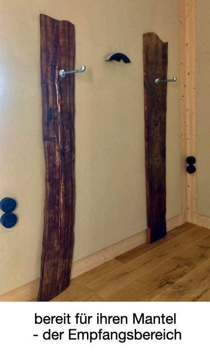 Empfangsbereich mit rustikalen Holzpaneelen als Garderobe und hellem Holzfußboden.