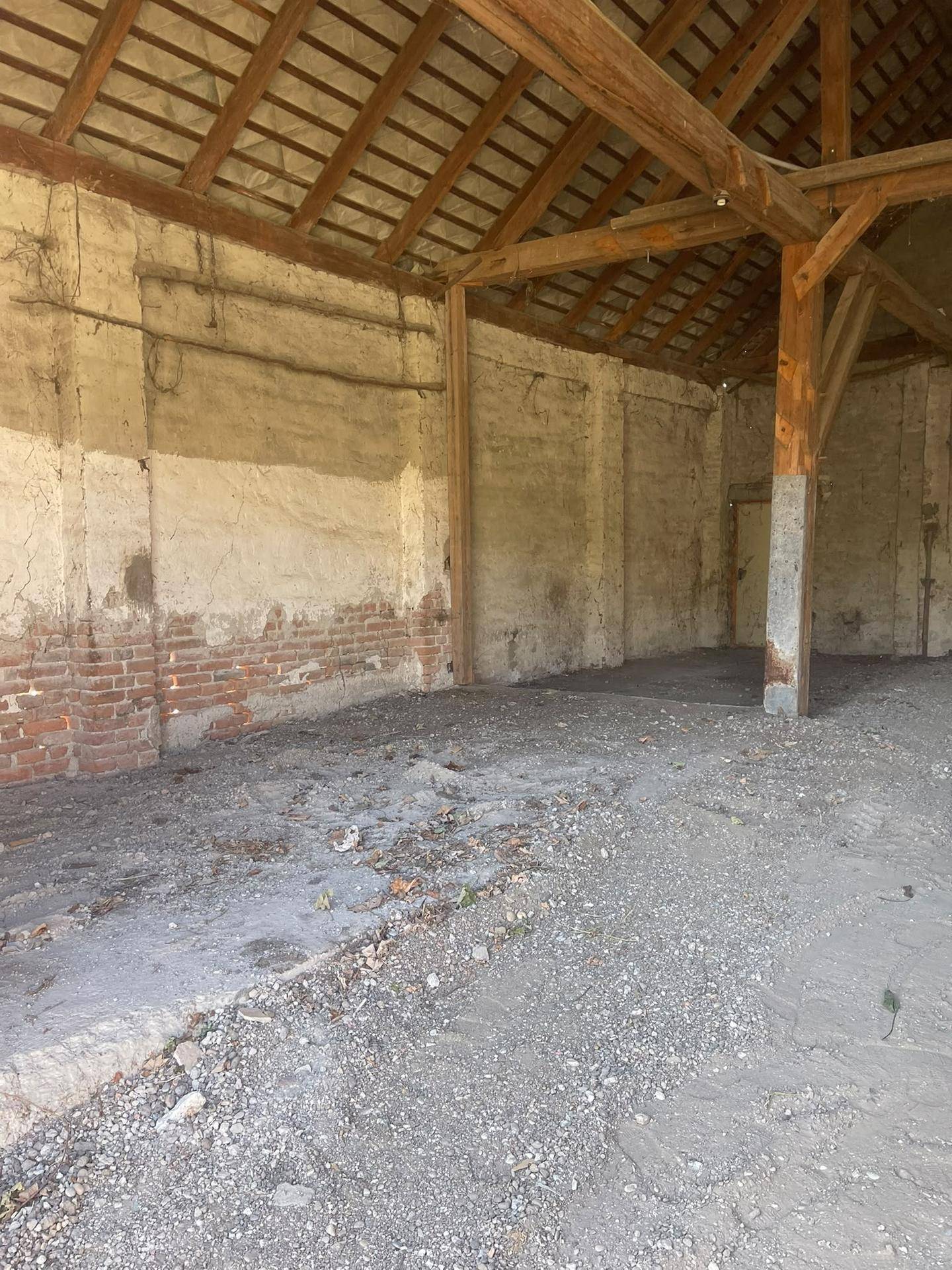 Detailansicht der Innenwände mit freiliegenden Ziegeln, Putz und robusten Holzbalken im Lagerraum.