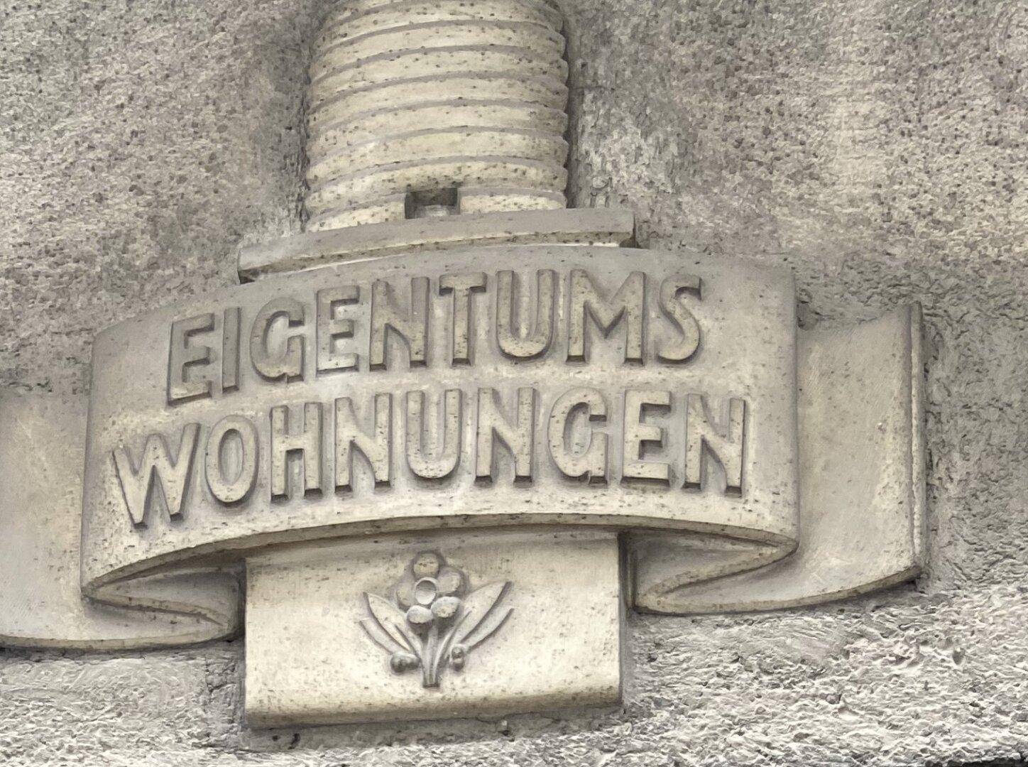 Detailaufnahme einer Steintafel mit der Inschrift "Eigentumswohnungen" an der Fassade.