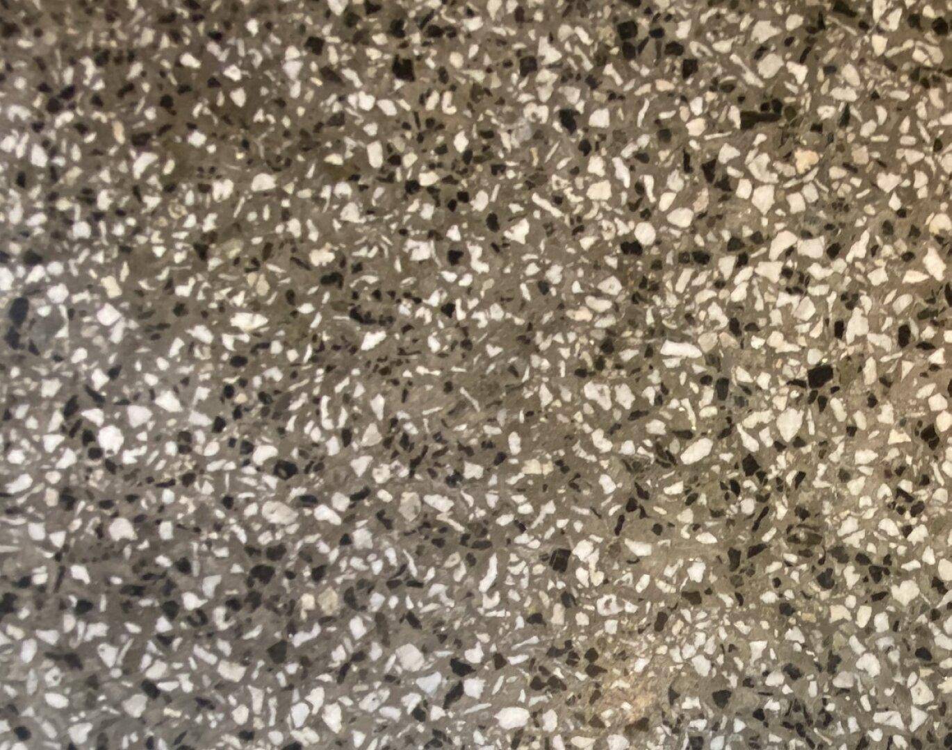 Nahaufnahme eines Terrazzobodens mit gesprenkelter Textur in Grau- und Weißtönen.