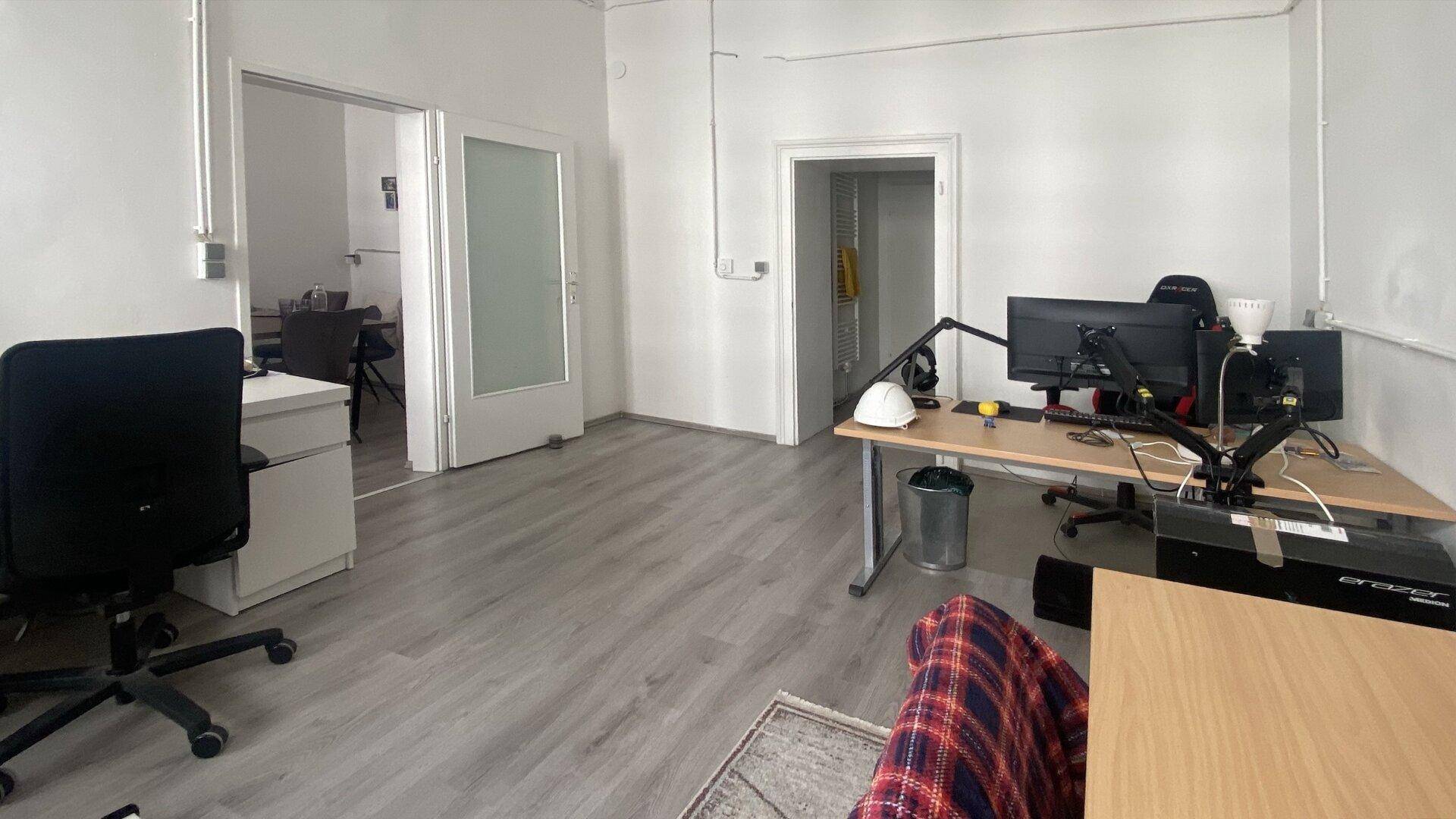 Bürobereich mit hellem Laminatboden und Türen, die zu weiteren Räumen führen, was eine flexible Nutzung ermöglicht.