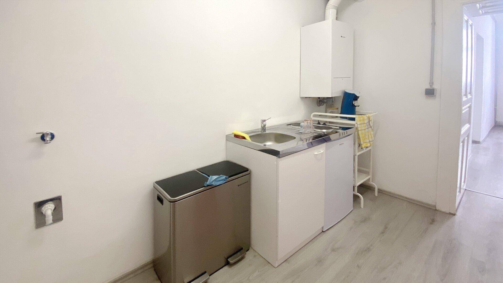 Kleiner Hauswirtschaftsraum mit Spülbecken, Unterschrank und einem Mülleimer, ideal für Reinigungsarbeiten.