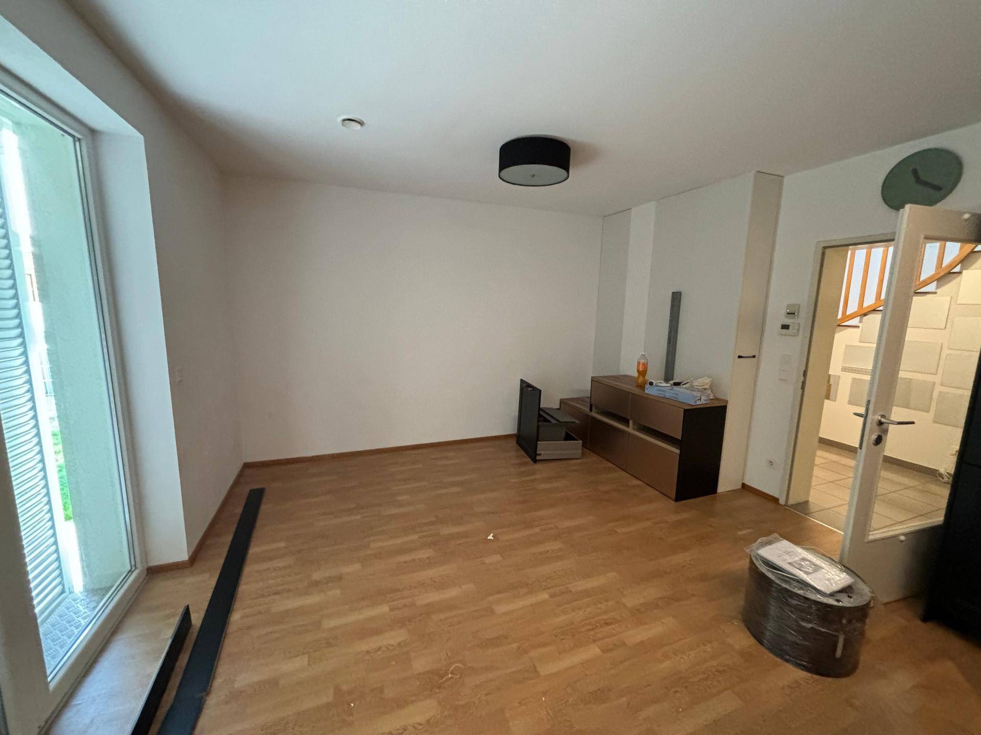 Helles Wohnzimmer mit Laminatboden und großem Fenster, bereit zur individuellen Gestaltung.