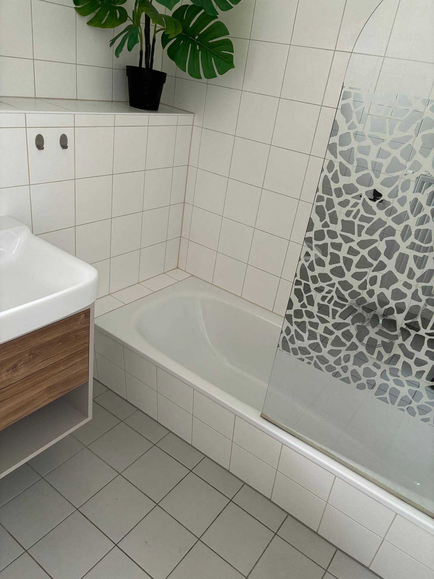 Modernes Badezimmer mit Badewanne, weißen Fliesen und einem stilvollen Waschtisch.
