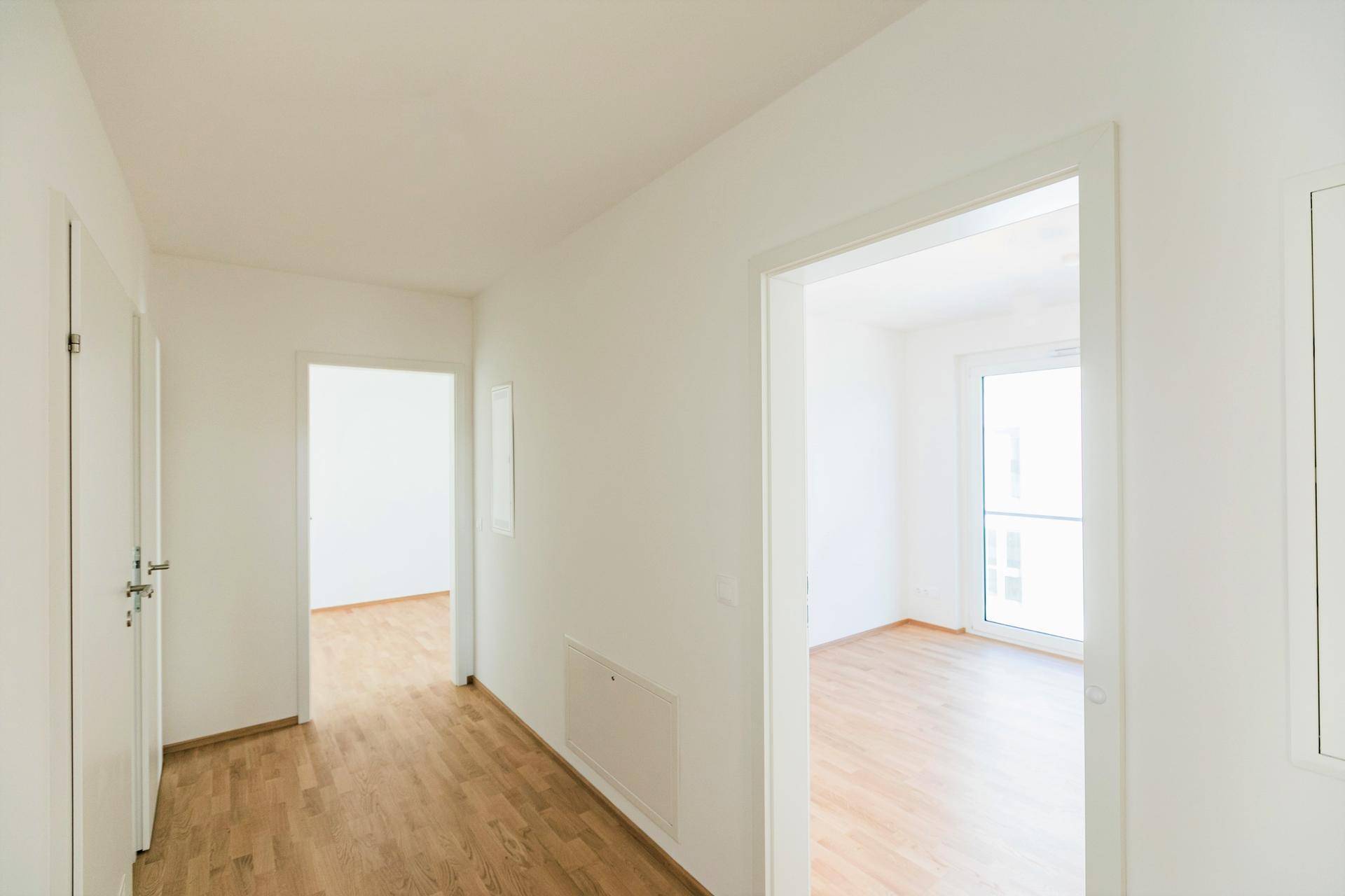 Heller Flur mit Parkettboden, der zu den verschiedenen Zimmern der Wohnung führt.