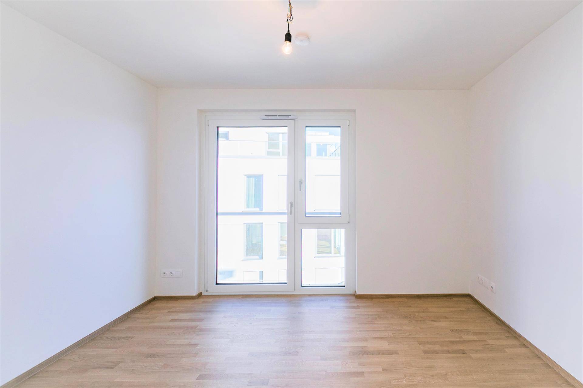 Geräumiges Zimmer mit Parkettboden und Fensterfront, die den Raum hell und einladend macht.