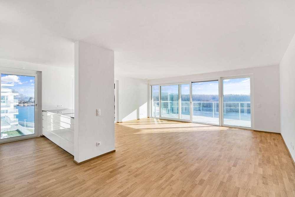 Heller, offener Wohnbereich mit Parkettboden und großen Schiebetüren zum Balkon mit Wasserblick.