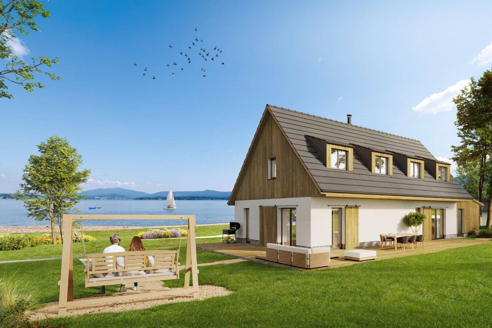 Modernes Haus am See mit Holzterrasse, Schaukel und Grillplatz, umgeben von grüner Landschaft.