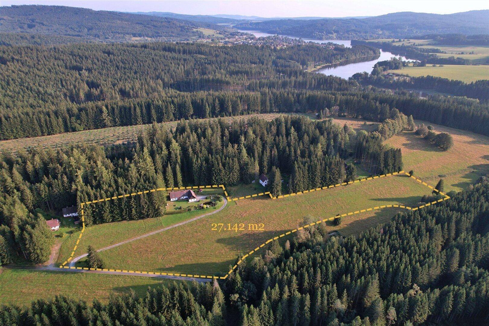 Luftaufnahme des weitläufigen Grundstücks mit Landhaus, umgeben von Wald und einem Fluss in der Ferne.