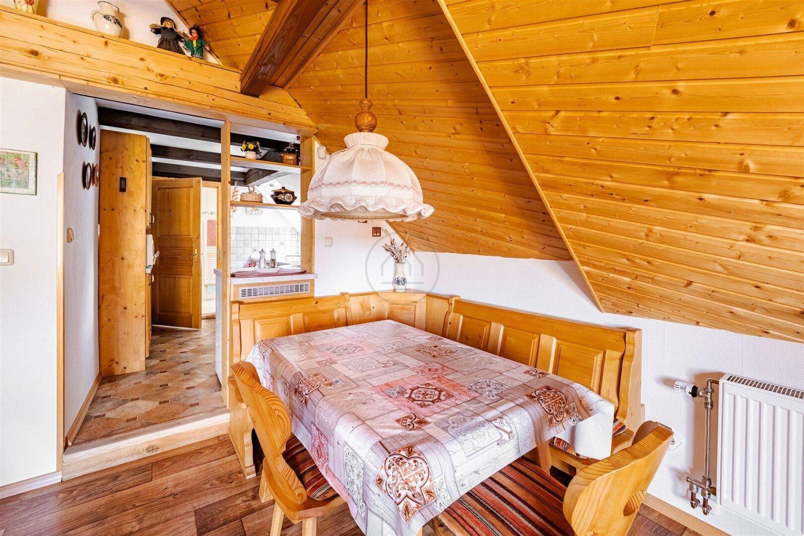 Gemütlicher Essbereich im Dachgeschoss mit Holztisch und Eckbank, ideal für gemeinsame Mahlzeiten.