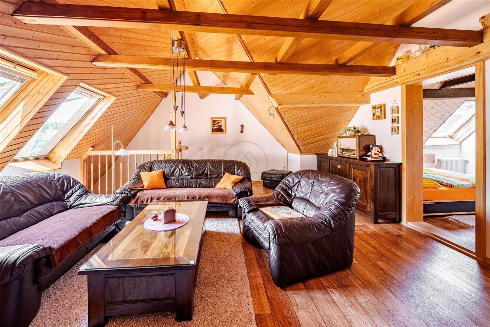 Heller Wohnbereich im Dachgeschoss mit Ledersofas, Holzboden und Dachfenstern, bietet viel Platz.