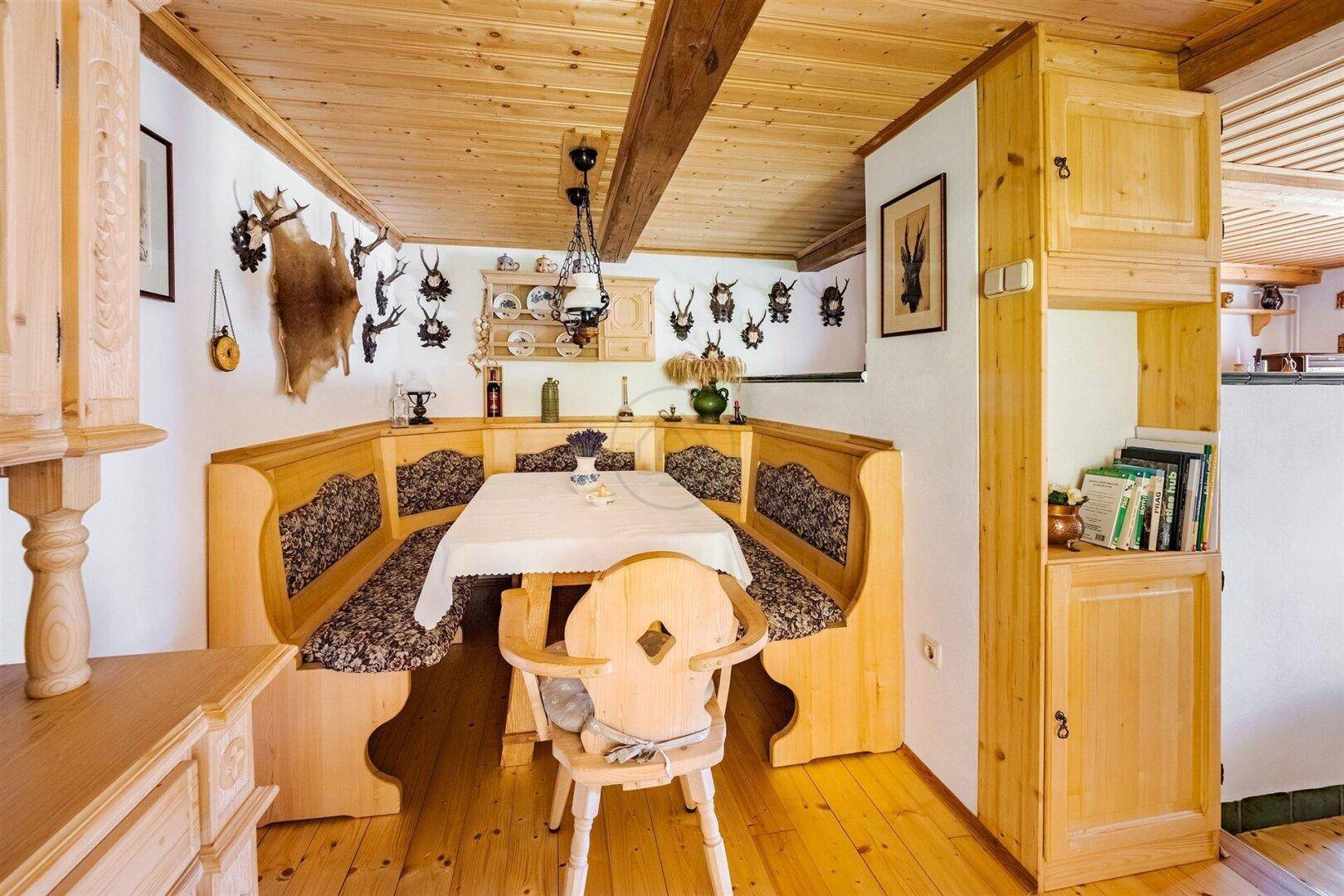 Traditioneller Essbereich mit Eckbank und Holztisch, dekoriert mit Jagdtrophäen und rustikalen Elementen.