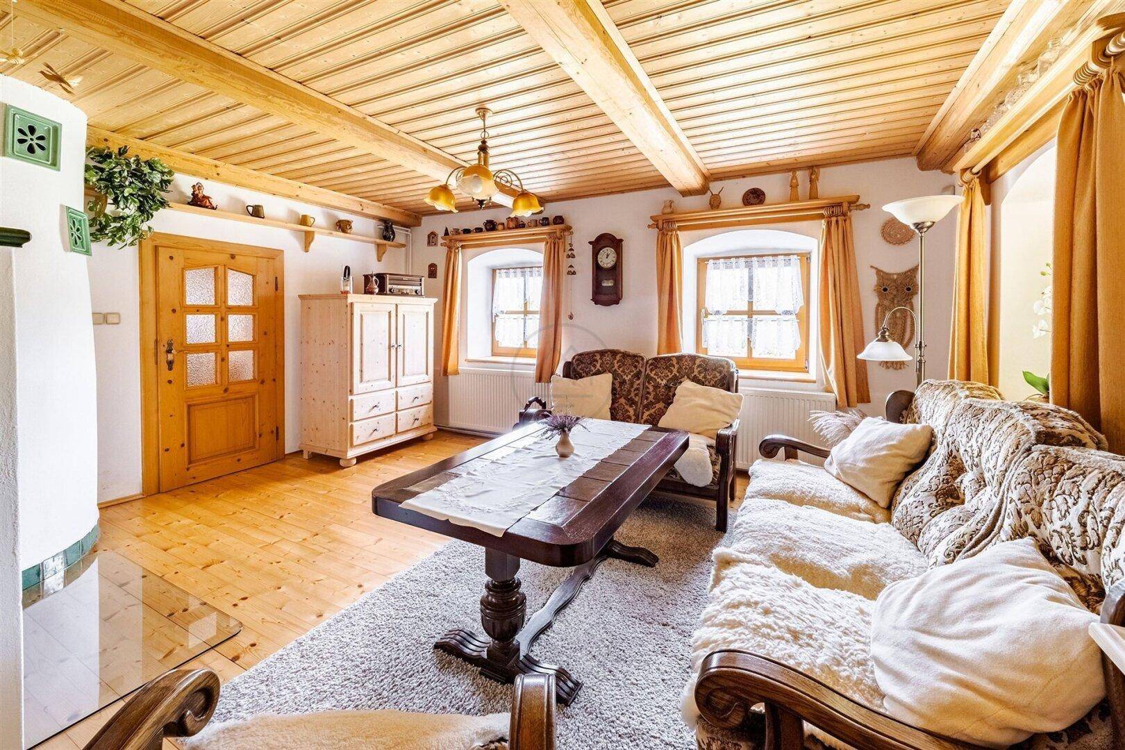Gemütliches Wohnzimmer im Landhausstil mit Holzbalkendecke, Holzboden und traditionellen Möbeln.