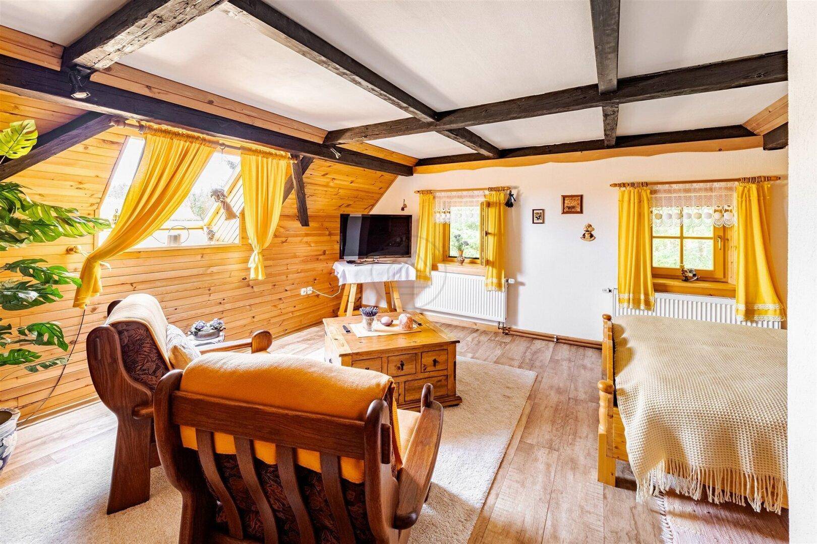 Helles Zimmer mit Holzvertäfelung, Holzboden und mehreren Fenstern, ideal als zusätzlicher Wohnbereich.