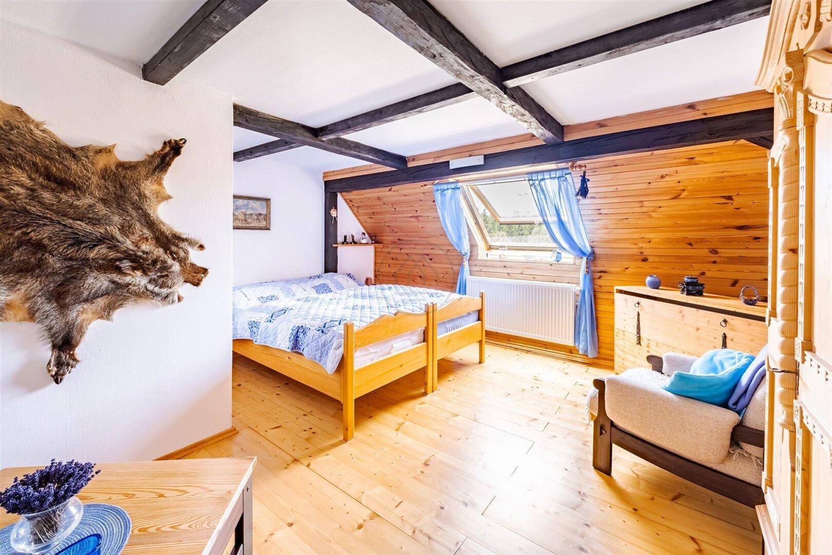 Rustikales Schlafzimmer mit Holzboden, sichtbaren Balken und einem Dachfenster, bietet eine ruhige Atmosphäre.