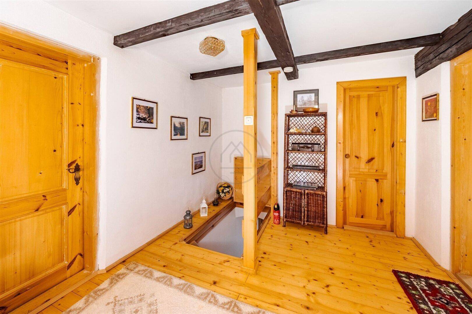 Oberer Flur mit Holzboden und sichtbaren Holzbalken, bietet Zugang zu den Zimmern.