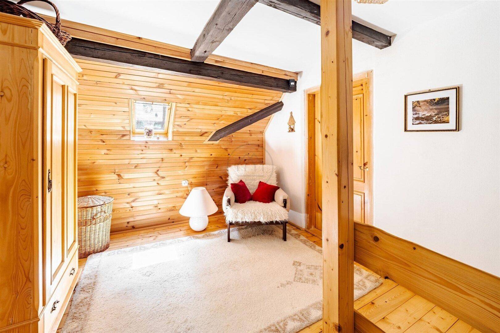 Gemütliches Schlafzimmer mit Holzvertäfelung, Holzboden und einem Dachfenster für natürliches Licht.