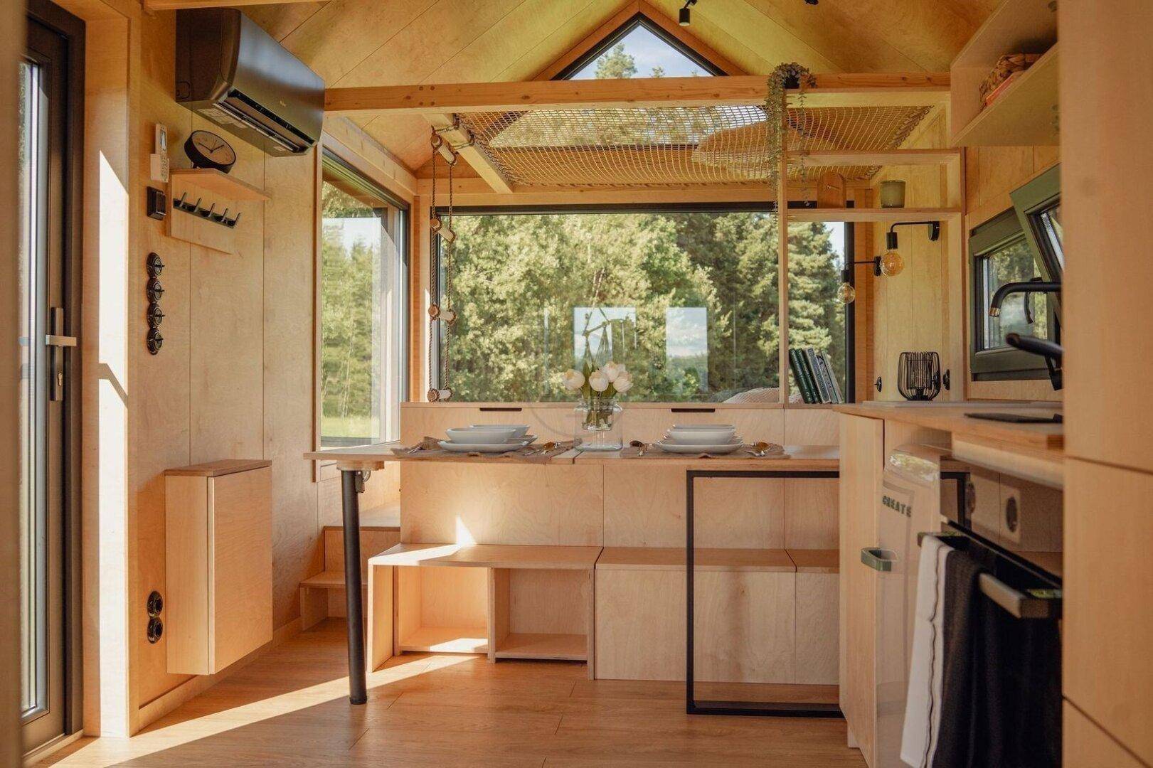 Heller Wohnbereich mit integrierter Küche, Holzelementen und weitem Blick in die Natur.