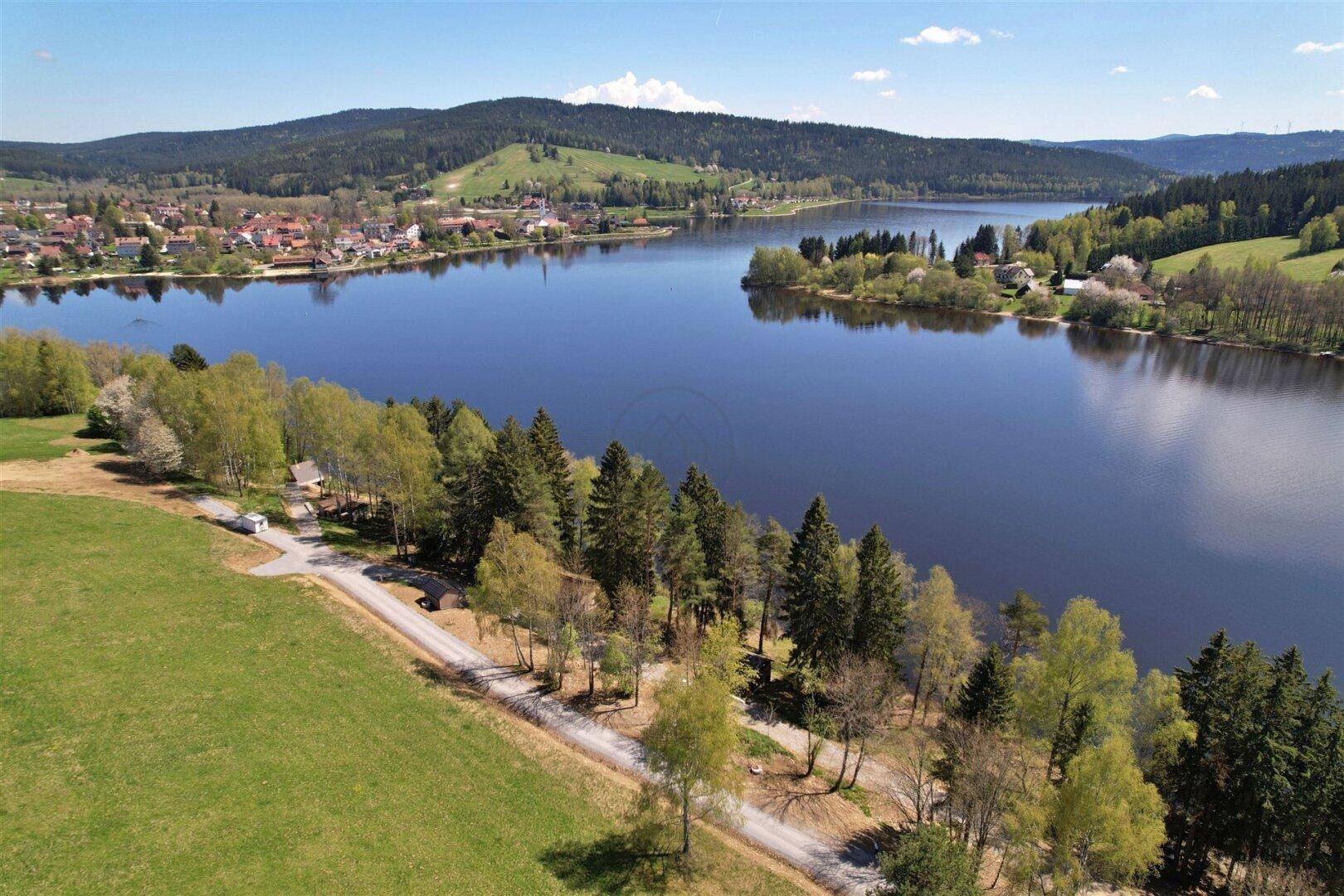 Panoramablick aus der Vogelperspektive auf den See, umgeben von Wäldern und Feldern.