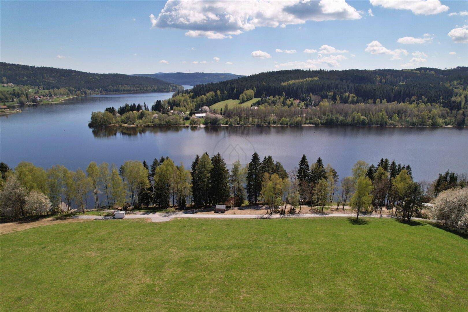 Luftaufnahme einer malerischen Seenlandschaft mit dichten Wäldern und weiten Feldern.
