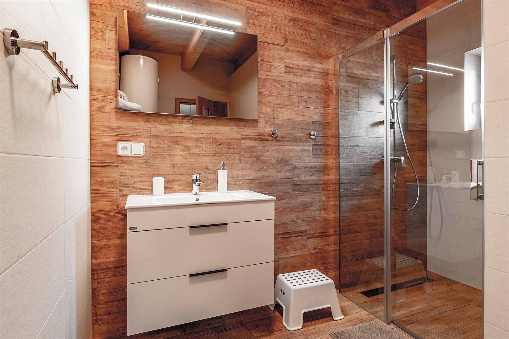 Modernes Badezimmer mit Holzwandverkleidung, begehbarer Dusche und Einzelwaschbecken.