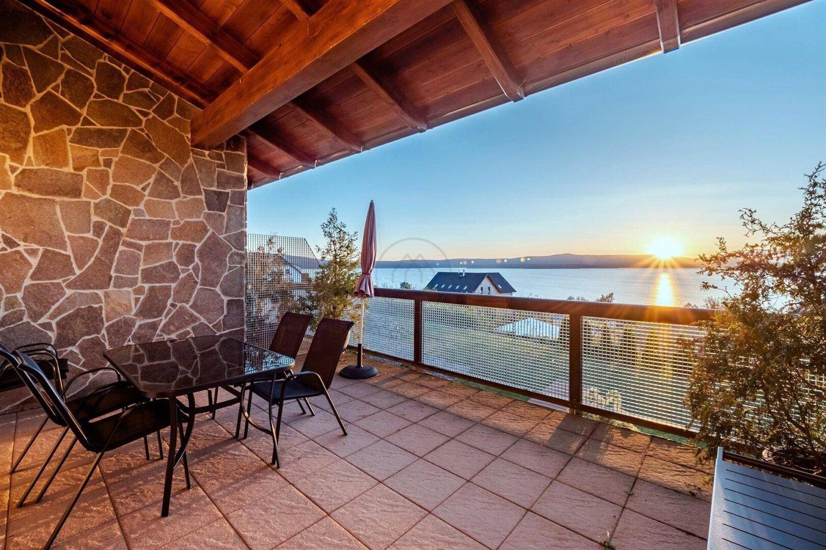 Sonnenuntergang auf der Terrasse mit Blick auf den See und die umliegende Landschaft.
