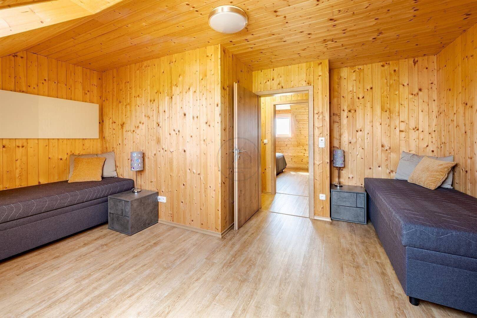 Schlafzimmer mit zwei Einzelbetten, Holzwänden und Laminatboden.