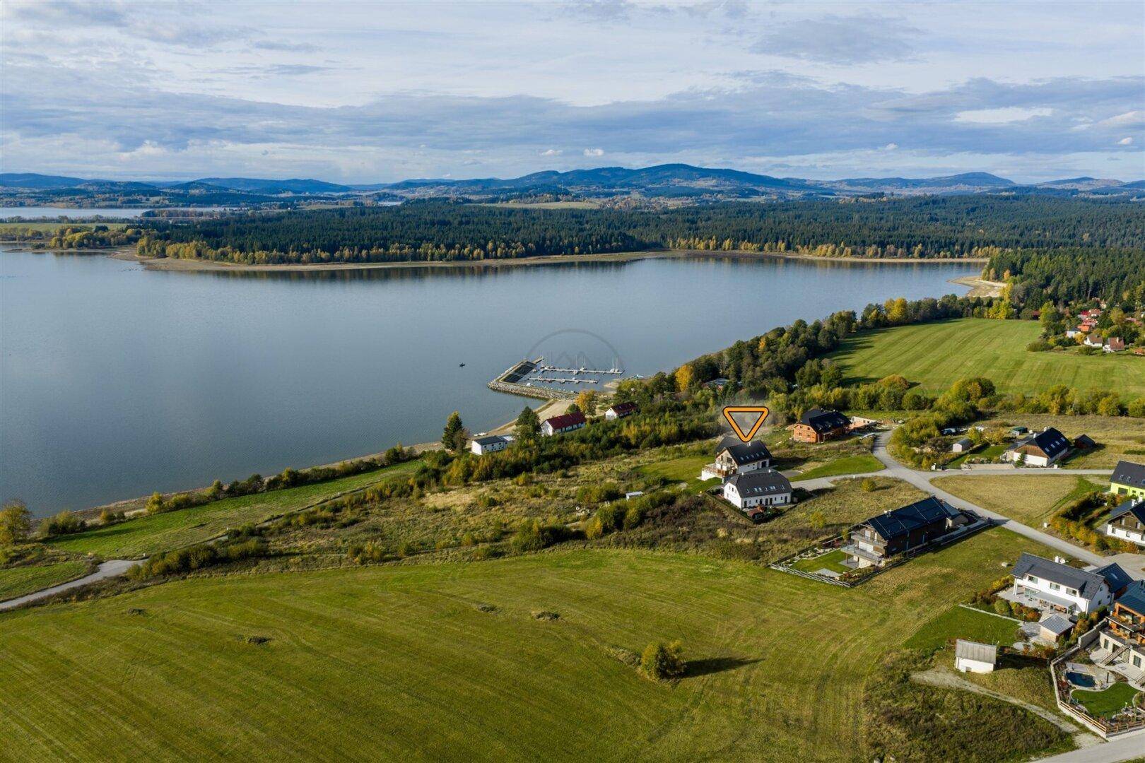 Luftaufnahme der Seenlandschaft mit Häusern und einem kleinen Hafen.